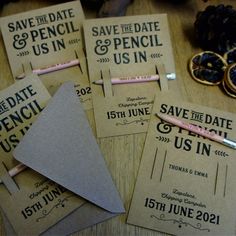 wedding save the date cards and pencils on a wooden table with other items around them