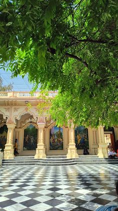 people sitting on benches in front of a building with paintings on the walls and ceiling