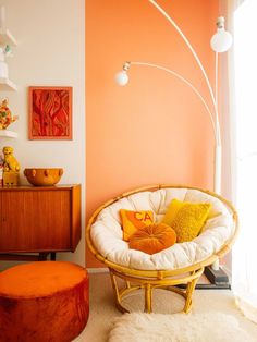 an orange and white living room with a round chair, ottoman and side table in the corner