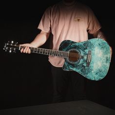 a man holding an acoustic guitar in the dark