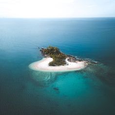 an island in the middle of the ocean with blue water and white sand on it