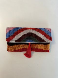 This uzbek  ikat velvet clutch bag with tassel  will make a great birthday gift for the ladies in your family.  Use it as an accessory that will turn heads and make every outfit stand out. The bag is decorated with a fashionable tassel. The traditional ikat fabric is handwoven with a lot of care in small villages in Uzbekistan. Who is this clutch for?  Product details: *Outer:  silk velvet ikat fabric *Inner: organic cotton lining *Length: 12  inches / 30 cm approx. *Width: 7   inches / 17 cm ap Rectangular Tassel Clutch For Parties, Rectangular Party Clutch With Tassels, Rectangular Tasseled Clutch As Gift, Multicolor Clutch For Celebration, Velvet Clutch Bag, Uzbek Ikat, Bag With Tassel, Clutch Bag Wedding, Velvet Clutch