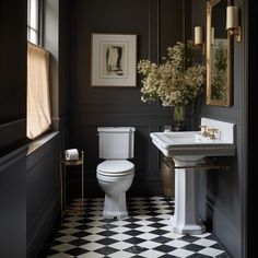 a white toilet sitting next to a sink in a bathroom under a framed painting on the wall