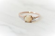 an opal and diamond ring on a white surface