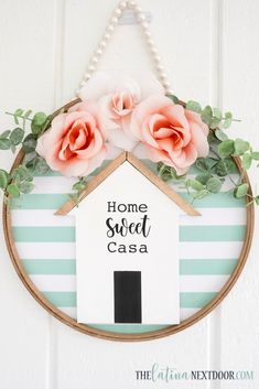 a sign that says home sweet casa hanging on a wall with pink flowers and greenery