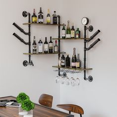 a wall mounted wine rack with bottles and glasses on it next to a dining room table