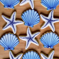 cookies decorated with blue and white icing are arranged on a wooden surface, along with starfish