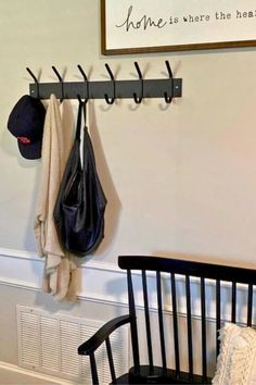 a coat rack and hat hanger in the corner of a room with a black chair