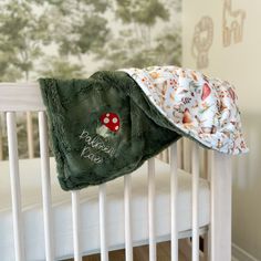 a baby's crib with a blanket on top of it and a bed in the background