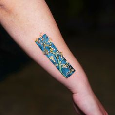 a person's arm with a blue and yellow piece of paper tattooed on it