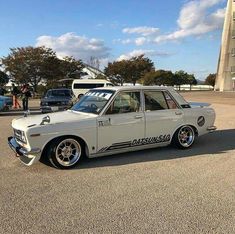 an old white car parked in a parking lot