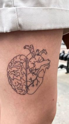 a woman's thigh with a tattoo of a heart and a brain on it