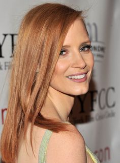 a woman with long red hair smiling at the camera