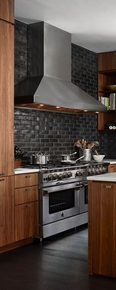 a kitchen with wooden cabinets and stainless steel stove top oven, range hood and shelving