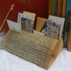 a pen holder made out of bamboo with money sticking out of it and some books in the background