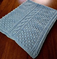 a blue knitted blanket sitting on top of a wooden table