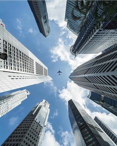 an airplane is flying through the sky between tall buildings