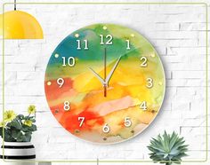 a colorful clock is on the wall next to a potted plant and a lamp