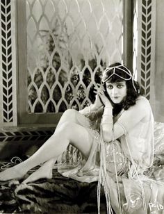 a woman sitting on top of a bed next to a window wearing a head piece