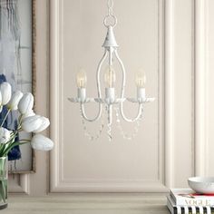 a white chandelier hanging from the ceiling next to a vase with tulips