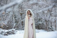 a pregnant woman wearing a fur coat in the snow with her hands on her head