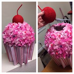 a cupcake decorated with pink flowers and a cherry in the middle is being held up