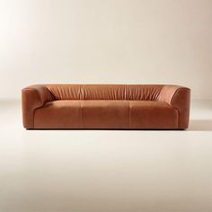 a brown leather couch sitting on top of a white floor