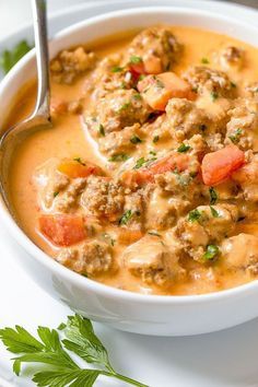 a white bowl filled with meat and vegetable soup next to a spoon on top of a plate