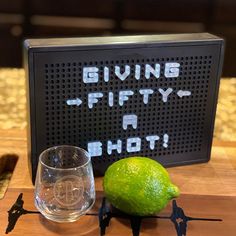 a lime sitting on top of a cutting board next to a glass