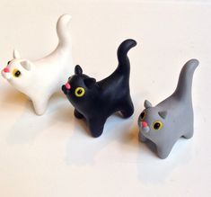 three small black and white cats sitting next to each other on top of a table