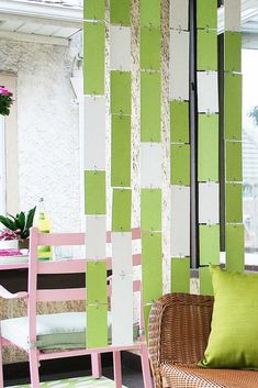 a living room filled with furniture and green wall paper on the walls, next to a wicker chair