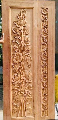 an intricately carved wooden cabinet with flowers and leaves on it's sides, in front of a building