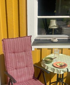 a chair sitting next to a small table with food on it and a window in the background