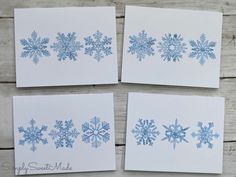 four cards with blue snowflakes on them sitting next to each other in front of a wooden background