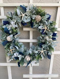 a wreath with starfishs, seashells and greenery hanging on a wall