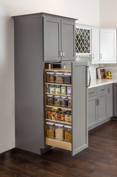 an open pantry in the middle of a kitchen with wooden floors and white walls,