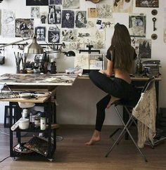 a woman sitting at a desk with lots of pictures on the wall