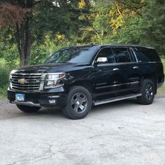 a black truck parked in front of some trees