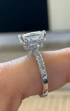 a woman's hand holding an engagement ring with a diamond band on the side