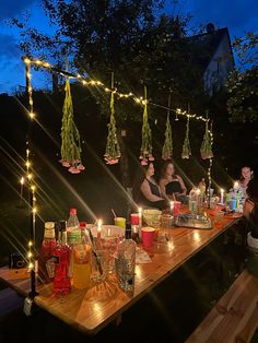 two people sitting at a table with drinks and candles in front of them on a dark night