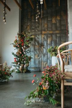 flowers are arranged on the floor in front of a wooden door and chairs with hanging lights