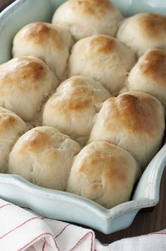 a blue dish filled with rolls on top of a wooden table