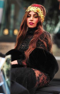 a woman with long hair sitting on the ground wearing a black dress and headband