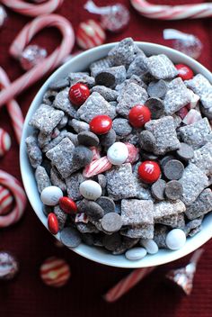 a bowl filled with candy canes and candies on top of a red table cloth