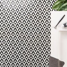 a black and white tiled wall next to a potted plant