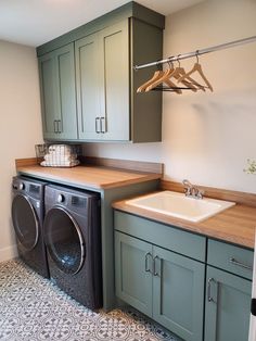 a washer and dryer in a small laundry room with green cabinetry, counter tops and drawers