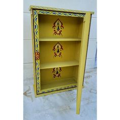 a yellow painted cabinet with decorative designs on it