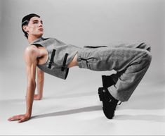 a man in grey sweatpants and black sneakers doing a handstand on one leg