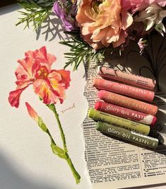 a bouquet of flowers sitting on top of an open book next to some lip glosses