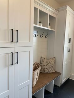 a mud room with white cabinets and black tile flooring on the walls, along with a bench in front of it